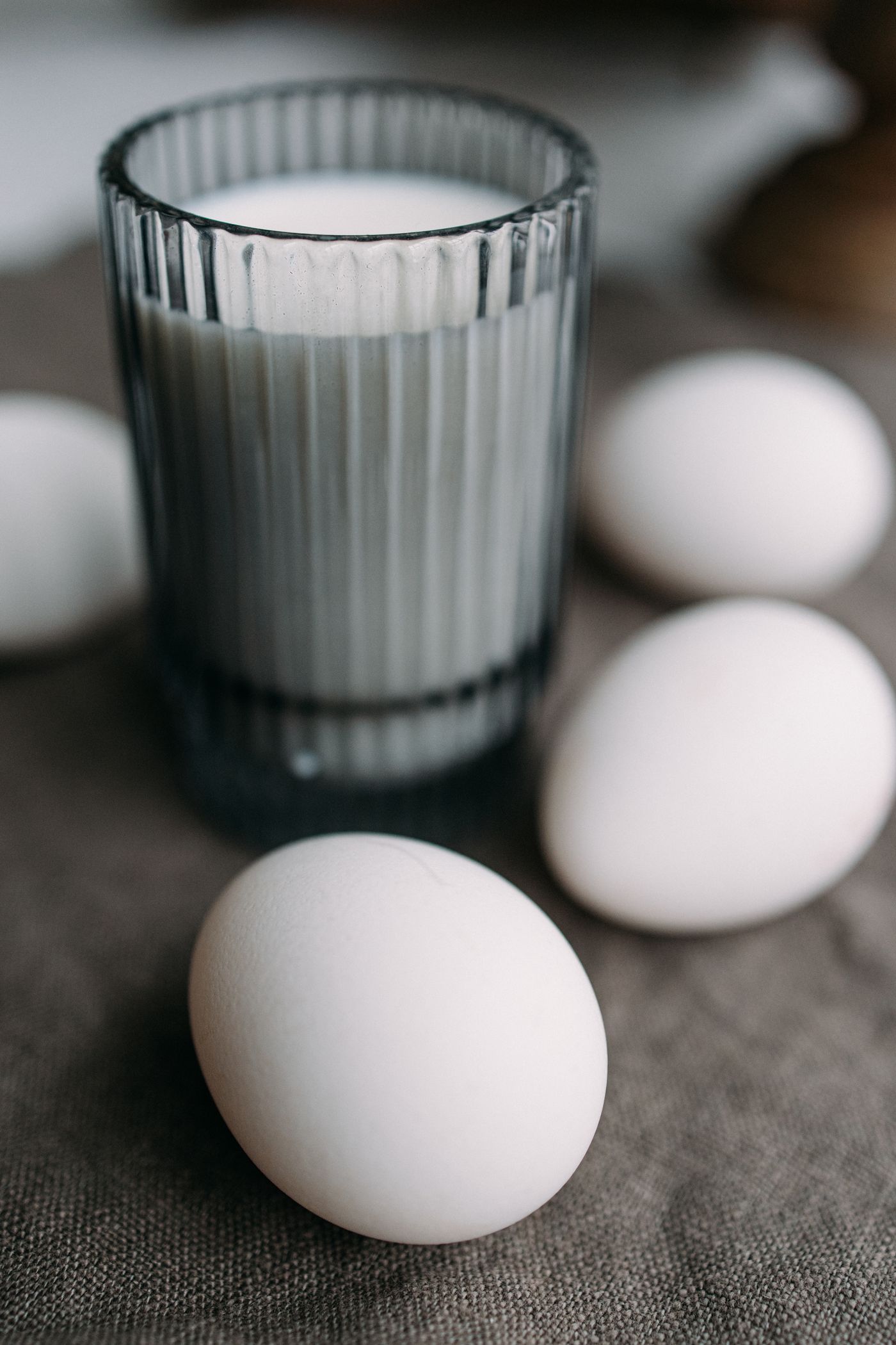 Ein Glas Milch und weiße Eier auf einem Leinentuch