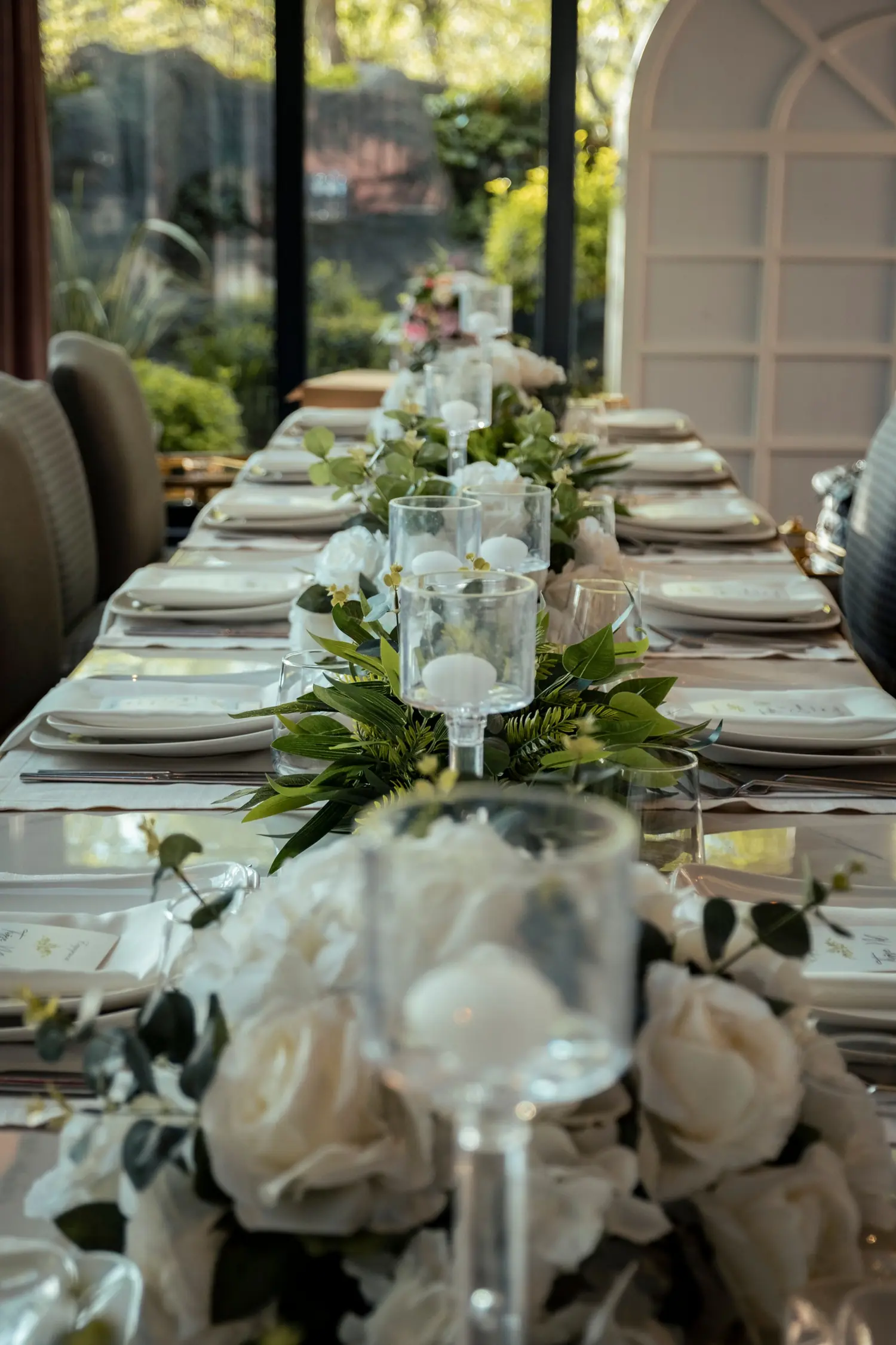 Festlich gedeckte Tafel mit weißen Rosen und Grün